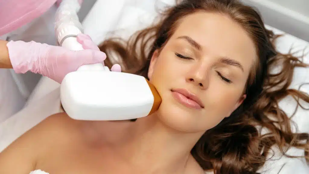 Woman-Receiving-Skin-Treatment-With-Laser-Device-On-Her-Cheek-From-A-Therapist-Wearing-Pink-Gloves.